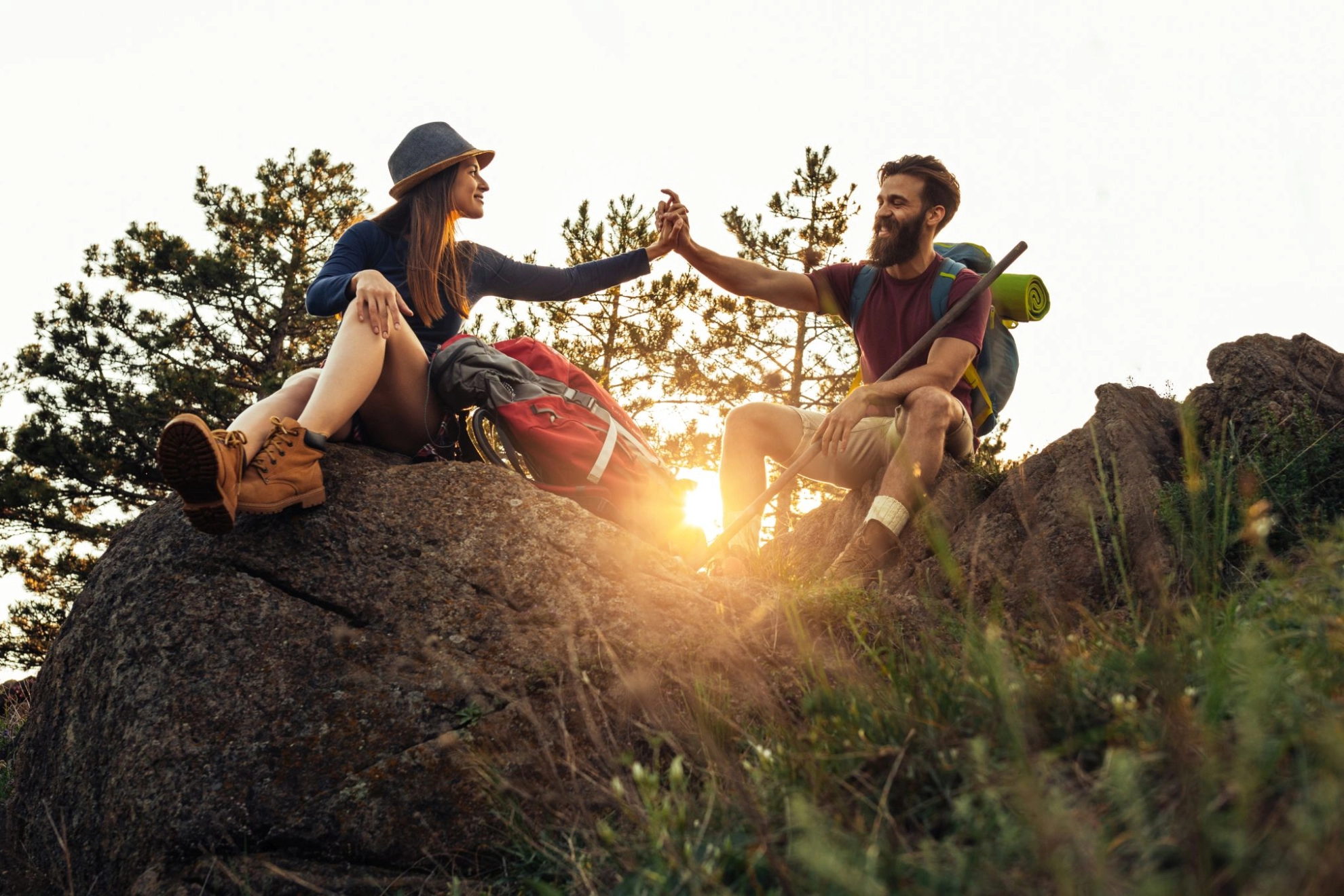 Wanderpaar sitzt vor Sonnenuntergang auf Felsgipfel